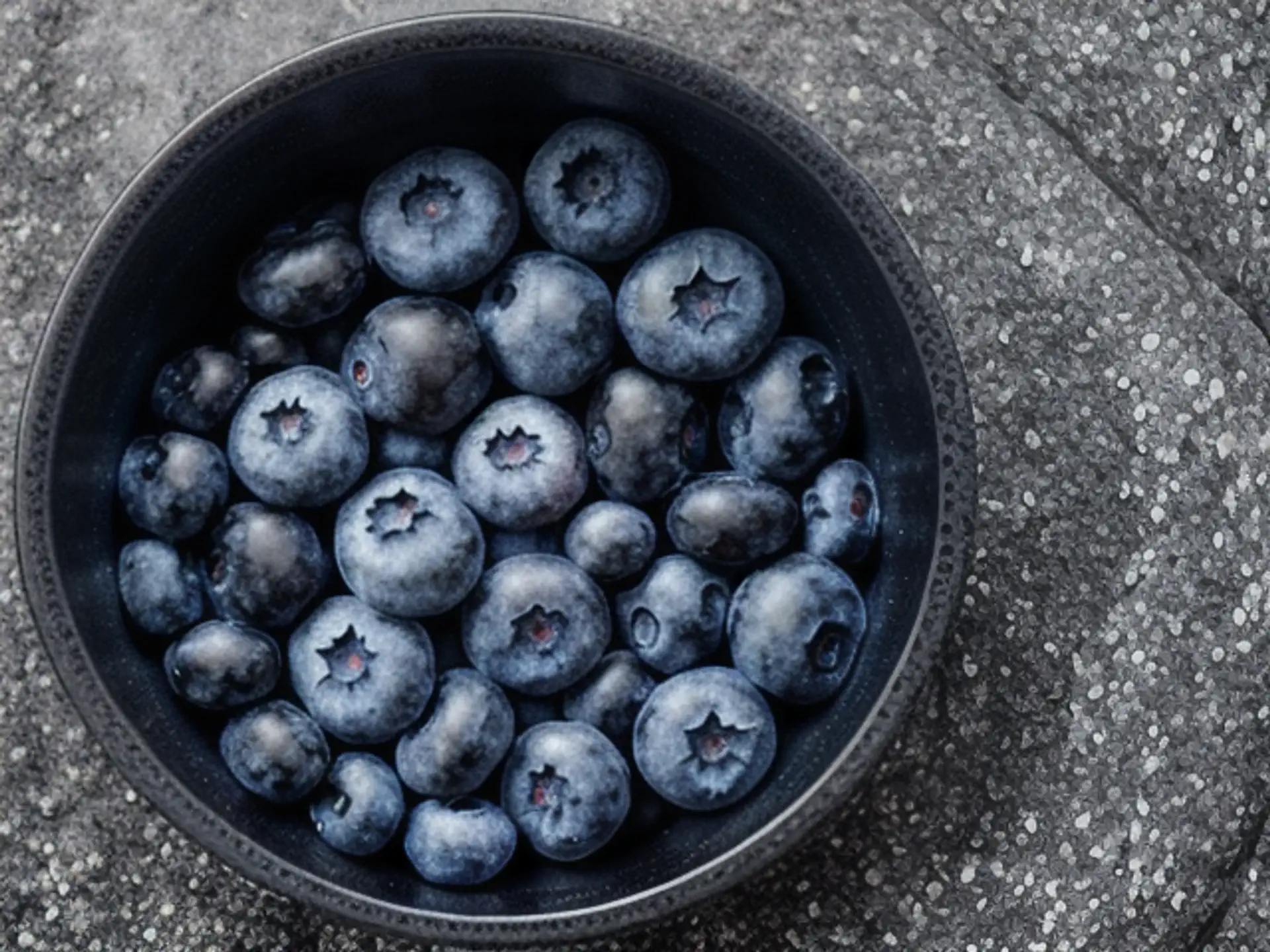 Verse blauwe bessen in zwarte kom - natuurlijke food fotografie