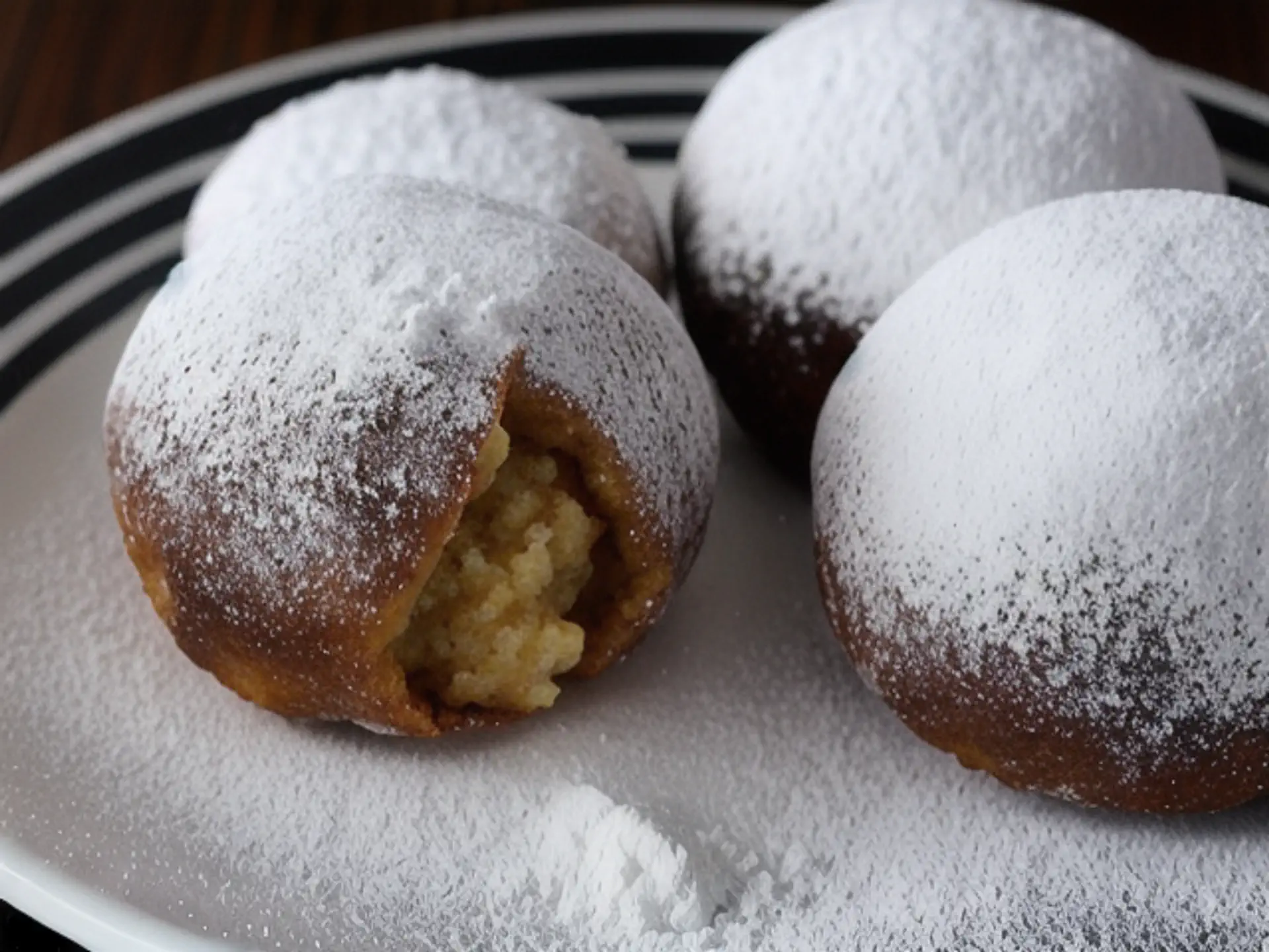 Verse Berliner bollen met poedersuiker en vanillevulling op wit bord