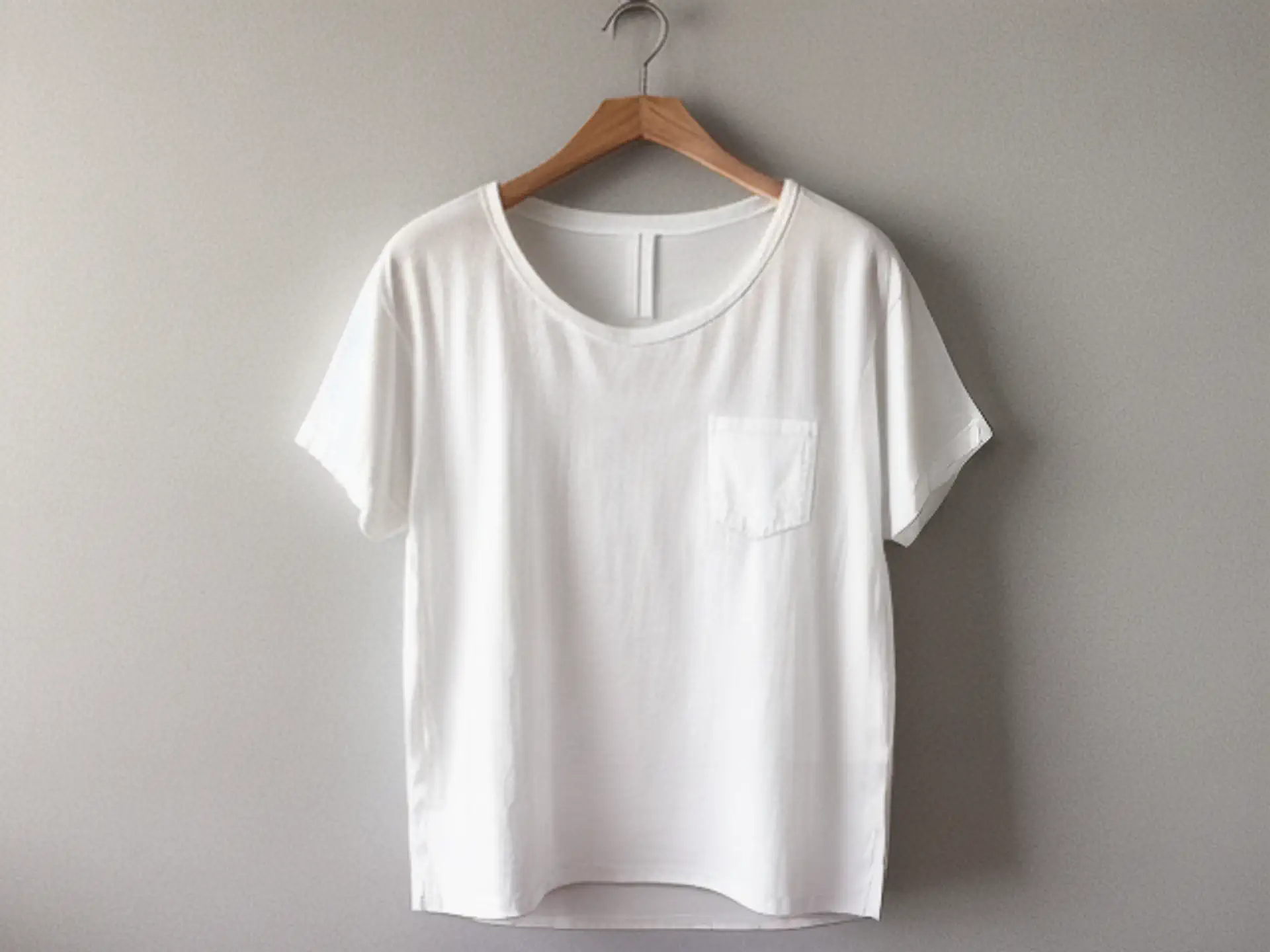 Minimalistisch wit T-shirt op houten hanger tegen grijze achtergrond