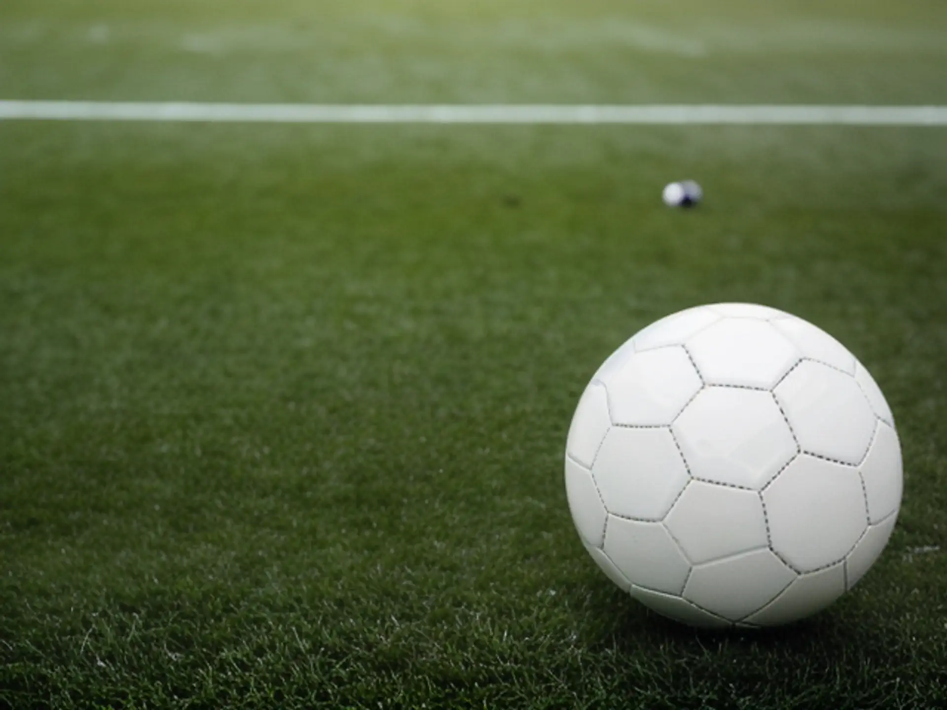 Witte voetbal op groen kunstgrasveld met sfeervolle scherptediepte