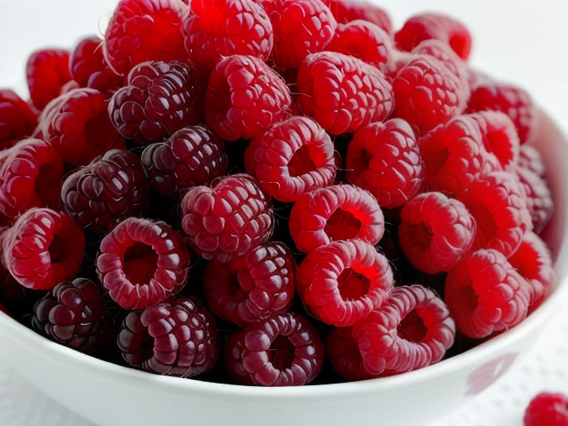 Verse rode frambozen in witte kom - close-up van sappig zomerfruit